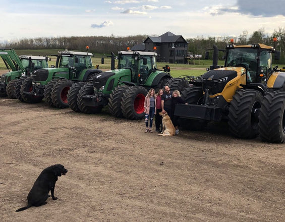 Vince and his family with their dog on the farm standing in front of their equipment